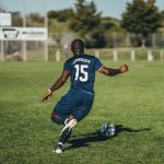 man in blue and white jersey shirt playing soccer during daytime